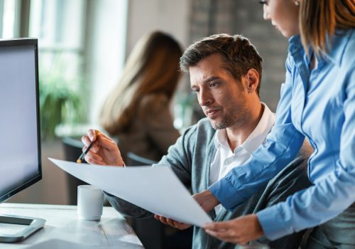 Two business colleagues examining documents while working together in the office.